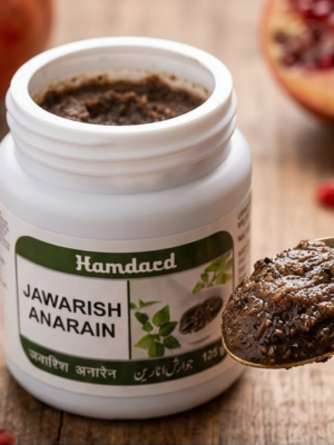 Close-up photo of a traditional Unani brass spoon scooping Hamdard Jawarish Anarain, revealing its rich, dark-brown paste texture on a wooden surface.