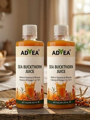 Two bottles of ADVEA Sea Buckthorn Juice standing on a rustic wooden table in a brightly lit kitchen.
