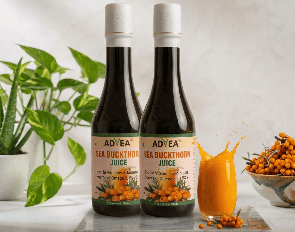 Premium ADVEA Sea Buckthorn Juice dark glass bottle featuring an elegant matte white cap with a gold rim accent. The bottle stands on a white marble slab next to a splashing glass of vibrant orange juice, fresh sea buckthorn berries, and a potted green plant on a bright, modern kitchen counter backdrop.